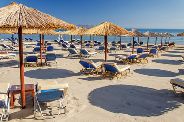 Straw beach umbrellas and sun chairs on a sandy beach on the east coast of Zakynthos island in Greece