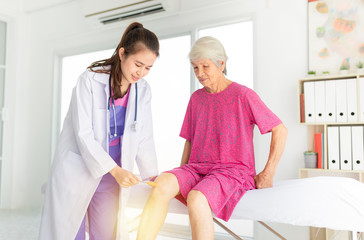 Obraz premium smart asian female doctor use hammer jerk hit to knee of patient, she assess knee symptom of patient ,elderly rehabilitation clinic, they training to rehab muscle, replacement of knee osteoarthritis