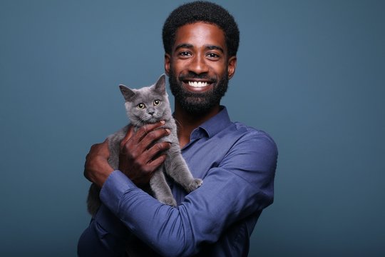 Beautiful afro man with a cute cat in front of a background