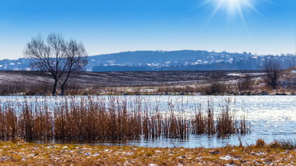 Winter landscape with river and field in sunny weather