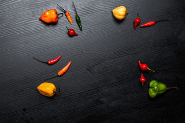 
Various types of peppers on black wooden table. Top view

