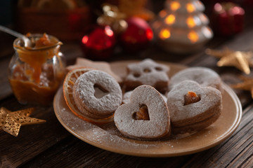Traditional Christmas Homemade Linzer Cookies on a plate surrounded by Christmas decor and burning candles. Close-up, selective focus. Still life in vintage style