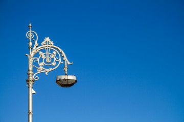 Fototapeta na wymiar Ornate wrought iron street light lamp in Dublin, Ireland, Europe. Old fashioned lamp post with curlicues and shamrocks against blue sky with copy space