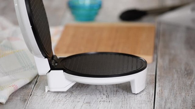 Making fresh hot waffles in the waffle maker for food. Preparation of wafers from fresh dough.