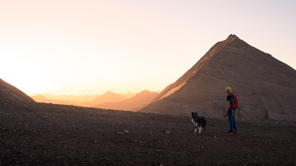 Hiker with dog at an idyllic sunrise in the Alps