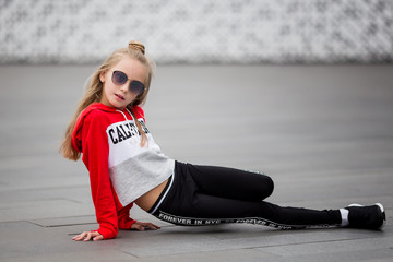Little girl in a tracksuit is dancing modern dance on the street. Young urban hip hop dancer