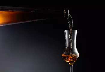 Fotobehang Aged golden fortified wine from the antique bottle being poured into a crystal glass. © Igor Normann