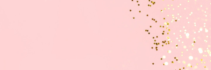 Banner with golden stars confetti scattered on a pink pastel background. Holidays concept with copy...
