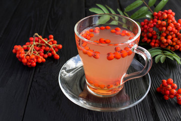 Closeup of autumn drink with red rowan on black surface