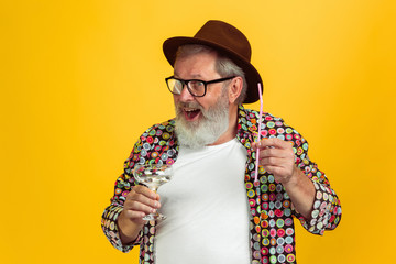 Time to drink. Portrait of senior hipster man in eyewear isolated on yellow studio background. Tech...