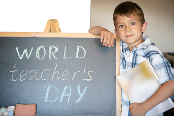 World Teacher's Day greeting, pupil boy near the chalkboard, chalk inscription text