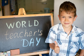 World Teacher's Day greeting, pupil boy near the chalkboard, chalk inscription text
