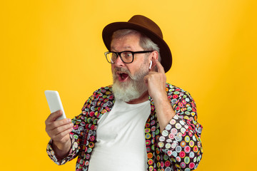 Blogger, vlogger, streamer. Portrait of senior hipster man in eyewear isolated on yellow studio...