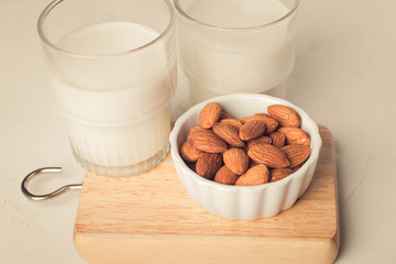 Close up. Almonds in a white ceramic cup and a milk glass.
