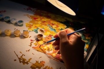 artist's hand paints a picture with oil paints