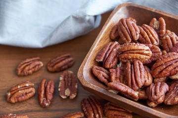pecan nuts in wood bowl on old brown table, selective focus. top view. Healthy food and snack.