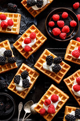 Waffles with the addition of vanilla cheese, raspberries and blackberries on a black background top view