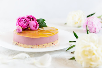 Obraz na płótnie Canvas Mousse cashew cake with orange and cherry, decorated with roses and peonies. Sugar, lactose, gluten free. Healthy food, vegan.