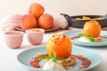Roasted peaches with lemon, lime and basil creme fraiche and raspberry coulis. Tasty sweet fruit dessert ala Gordon Ramsey. Top down view, white wooden table background.