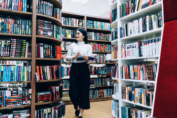 Young female walking with coffee in book shop