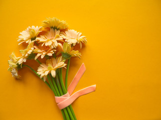 Bunch of soft beige gerbera on orange background. Minimal simple modern floral concept. Top view with copy space. Bunch of yellow flowers
