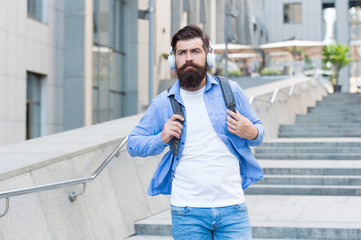 Listen to it, live it. Bearded man listen to music urban outdoors. Hipster wear headphones in casual style. New technology. Modern life. Summer vacation. Journey and trip. Listen and enjoy