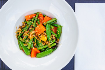 Plate of baked green beans mixed with pea pods and carrot