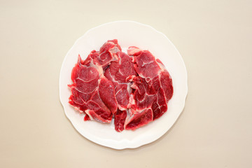 Raw beef meat steak on white plate on light background top view. Close up. Carnivore, keto