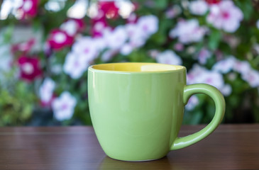 Coffee cup mockup on a table, blur green background.