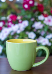 Coffee cup mockup on a table, blur green background.
