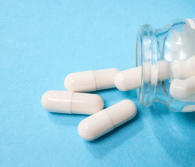white pills on a blue background in a transparent jar