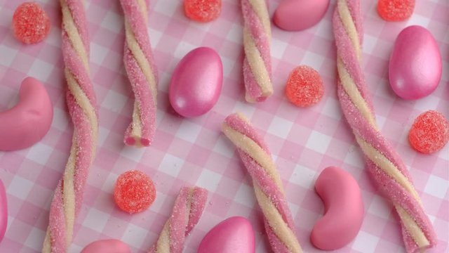 Candy sweets background. Assorted colorful chocolate candies and jelly stick. Pink color palette delicious sweets turning.