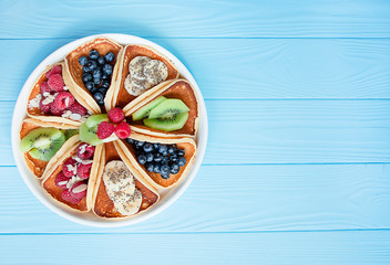 Classic American pancakes with fresh berries on a blue wooden background. Pancakes with fruit. Baner. Summer homemade breakfast. Copy space.