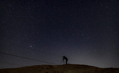 Silhouette of photographer taking pictures of the night sky