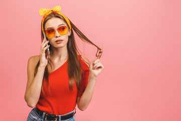 Portrait of a happy young business woman using mobile phone isolated over pink background.