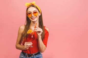 Close up portrait of attractive lovely girl holding coctail drink isolated over pink background.