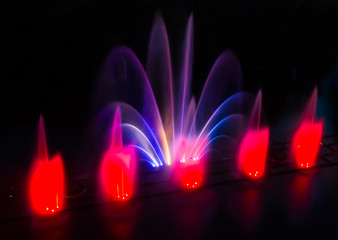 Colored fountain on the river at night.