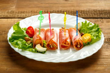 Ham rolls on a plate with cherry salad on a wooden table. save a place.
