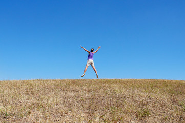 happy young woman jumping in the field