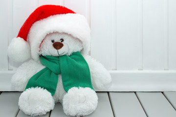 Child's stuffed toy. White teddy bear in a santa hat. Merry Christmas background.