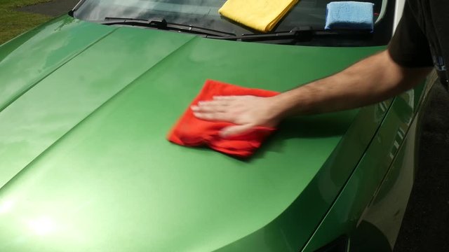 Buffing a green car with a red cloth