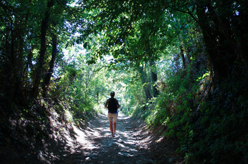 young woman with backpack walking in the forest