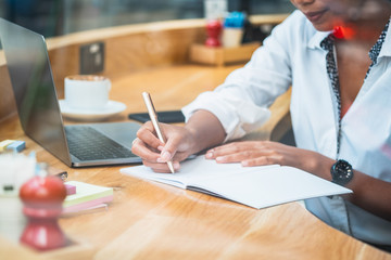 Unrecognizable woman writing in notebook behind glass window stock photo