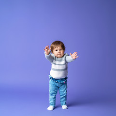 Full length excited baby, takes the first step on a purple background.