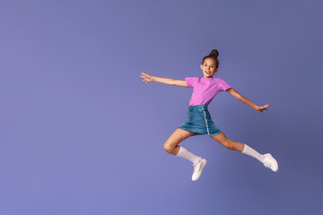 Fototapeta na wymiar happy fashionable girl jumps in air in full height, on purple background.