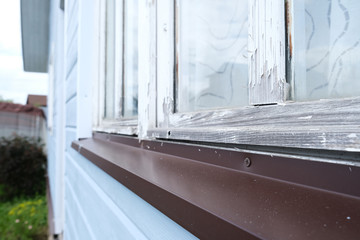 A part of white windows of a small tiny frame house with blue walls,a country residence in sunny...