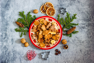 Christmas cookies background. Homemade cookies christmas trees on a red plate near fir branches and cones on a stone gray background, top view, flat lay