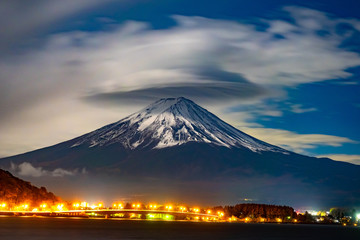 Japan. Lights of Kawaguchiko city at the foot of Fuji. The Volcano Fuji. Tourism in Japan. An active volcano in Japan. Fuji on the background of the cloudy sky. Kawaguchiko Landscape. Travel to Asia.
