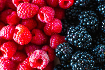Close-up of raspberry and black mulberry berries split frame. Summer vitamins, sweet berries.