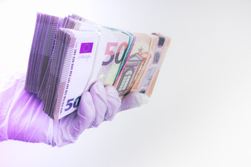 hand with gloves receiving, giving or holding euro cash banknote